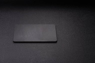 Siyah bir taş levha ya da tabak, boş bir mutfak aleti. Tasarımınız için yemek arkaplanı olarak siyah bir tahta.