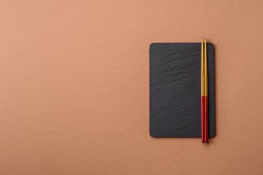 Siyah bir taş levha ya da tabak, boş bir mutfak aleti. Tasarımınız için yemek arkaplanı olarak siyah bir tahta.