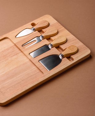 Tahta kesme tahtası ve dilimleme aletleri olan peynir bıçakları. Tasarımınız için yemek arkaplanı olarak peynir bıçakları