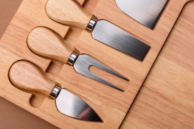 Tahta kesme tahtası ve dilimleme aletleri olan peynir bıçakları. Tasarımınız için yemek arkaplanı olarak peynir bıçakları