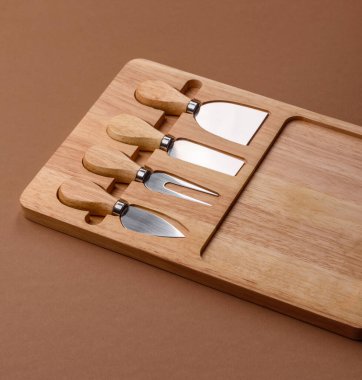 Tahta kesme tahtası ve dilimleme aletleri olan peynir bıçakları. Tasarımınız için yemek arkaplanı olarak peynir bıçakları