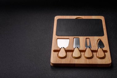 Tahta kesme tahtası ve dilimleme aletleri olan peynir bıçakları. Tasarımınız için yemek arkaplanı olarak peynir bıçakları