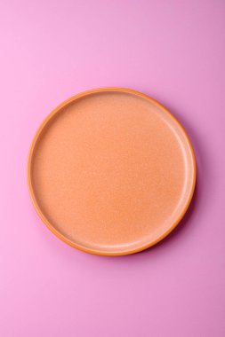 Mutfak malzemesi olarak pembe arka planda boş bir seramik tabak. Tasarımınız için yiyecek arka planı olarak boş bir tabak