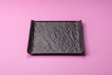 Mutfak malzemesi olarak pembe arka planda boş bir seramik tabak. Tasarımınız için yiyecek arka planı olarak boş bir tabak