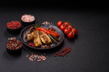 Vegetables such as corn, bell peppers, zucchini, and mushrooms grilled or barbecued, along with salt and spices for the dinner table. Grilled vegetables as a food background for your design