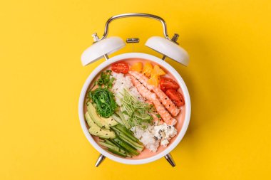 Pirinç, domates, sos ve sebzeli karides kasesi, Asya yemeği. Karides ya da karides, eski bir çalar saatin kadranı yerine tabak konsepti olarak kullanılır.