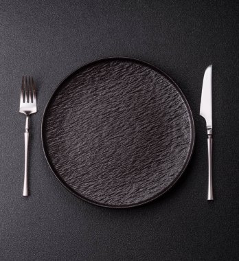 Boş bir seramik tabak, bıçak ve çatal yemek masası olarak kullanılıyor. Tasarımınız için arka plan olarak boş bir tabak