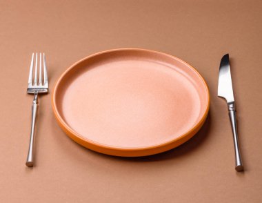 Boş bir seramik tabak, bıçak ve çatal yemek masası olarak kullanılıyor. Tasarımınız için arka plan olarak boş bir tabak