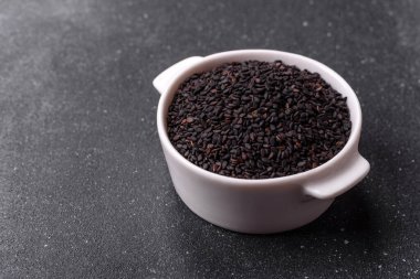 Bir kasede siyah susam tohumu, yağ ve sağlıklı yemek için bir malzeme. Tasarımınız için yiyecek arkaplanı olarak siyah susam