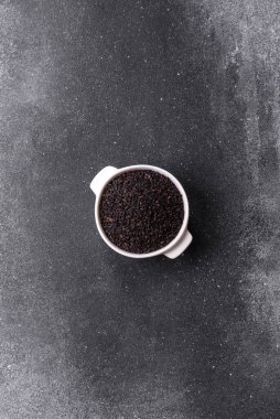 Bir kasede siyah susam tohumu, yağ ve sağlıklı yemek için bir malzeme. Tasarımınız için yiyecek arkaplanı olarak siyah susam