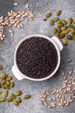 Bir kasede siyah susam tohumu, yağ ve sağlıklı yemek için bir malzeme. Tasarımınız için yiyecek arkaplanı olarak siyah susam