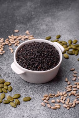 Bir kasede siyah susam tohumu, yağ ve sağlıklı yemek için bir malzeme. Tasarımınız için yiyecek arkaplanı olarak siyah susam