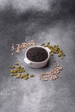 Bir kasede siyah susam tohumu, yağ ve sağlıklı yemek için bir malzeme. Tasarımınız için yiyecek arkaplanı olarak siyah susam