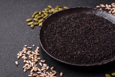 Bir kasede siyah susam tohumu, yağ ve sağlıklı yemek için bir malzeme. Tasarımınız için yiyecek arkaplanı olarak siyah susam