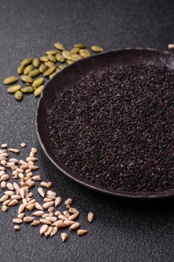 Bir kasede siyah susam tohumu, yağ ve sağlıklı yemek için bir malzeme. Tasarımınız için yiyecek arkaplanı olarak siyah susam