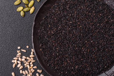 Bir kasede siyah susam tohumu, yağ ve sağlıklı yemek için bir malzeme. Tasarımınız için yiyecek arkaplanı olarak siyah susam