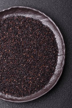 Bir kasede siyah susam tohumu, yağ ve sağlıklı yemek için bir malzeme. Tasarımınız için yiyecek arkaplanı olarak siyah susam