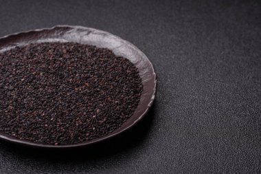 Bir kasede siyah susam tohumu, yağ ve sağlıklı yemek için bir malzeme. Tasarımınız için yiyecek arkaplanı olarak siyah susam