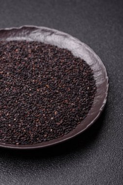 Bir kasede siyah susam tohumu, yağ ve sağlıklı yemek için bir malzeme. Tasarımınız için yiyecek arkaplanı olarak siyah susam