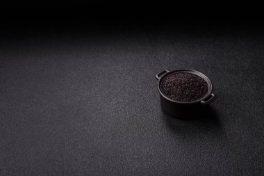 Bir kasede siyah susam tohumu, yağ ve sağlıklı yemek için bir malzeme. Tasarımınız için yiyecek arkaplanı olarak siyah susam