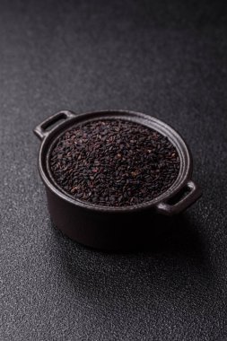 Bir kasede siyah susam tohumu, yağ ve sağlıklı yemek için bir malzeme. Tasarımınız için yiyecek arkaplanı olarak siyah susam