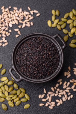 Bir kasede siyah susam tohumu, yağ ve sağlıklı yemek için bir malzeme. Tasarımınız için yiyecek arkaplanı olarak siyah susam