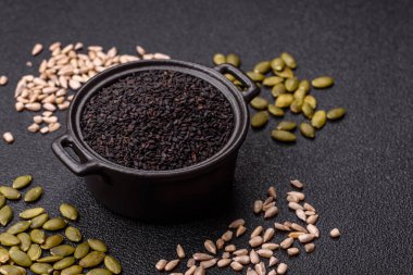 Bir kasede siyah susam tohumu, yağ ve sağlıklı yemek için bir malzeme. Tasarımınız için yiyecek arkaplanı olarak siyah susam