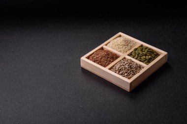 Bir kutu keten, balkabağı, ayçiçeği ve susam tohumu, sağlıklı beslenmek için malzemeler. Keten, susam, balkabağı ve ay çekirdeği tasarımınız için bir besin kaynağı.