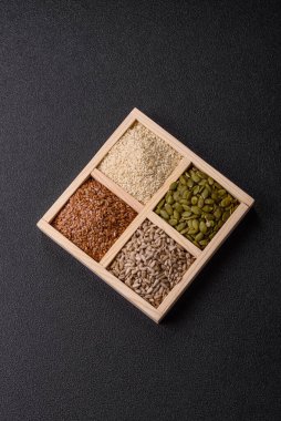 Bir kutu keten, balkabağı, ayçiçeği ve susam tohumu, sağlıklı beslenmek için malzemeler. Keten, susam, balkabağı ve ay çekirdeği tasarımınız için bir besin kaynağı.