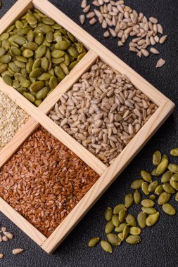 Bir kutu keten, balkabağı, ayçiçeği ve susam tohumu, sağlıklı beslenmek için malzemeler. Keten, susam, balkabağı ve ay çekirdeği tasarımınız için bir besin kaynağı.