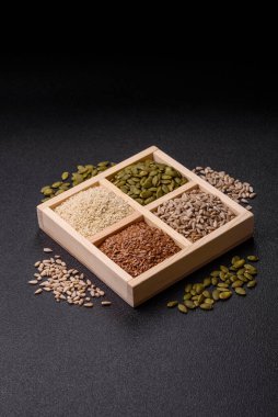 Bir kutu keten, balkabağı, ayçiçeği ve susam tohumu, sağlıklı beslenmek için malzemeler. Keten, susam, balkabağı ve ay çekirdeği tasarımınız için bir besin kaynağı.