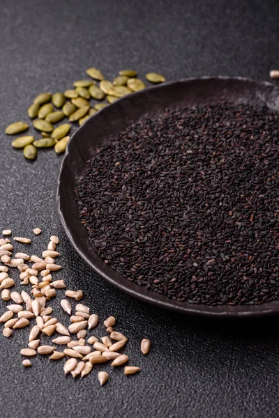 Bir kasede siyah susam tohumu, yağ ve sağlıklı yemek için bir malzeme. Tasarımınız için yiyecek arkaplanı olarak siyah susam