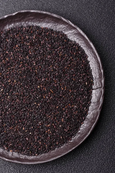 Bir kasede siyah susam tohumu, yağ ve sağlıklı yemek için bir malzeme. Tasarımınız için yiyecek arkaplanı olarak siyah susam