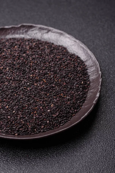 Bir kasede siyah susam tohumu, yağ ve sağlıklı yemek için bir malzeme. Tasarımınız için yiyecek arkaplanı olarak siyah susam