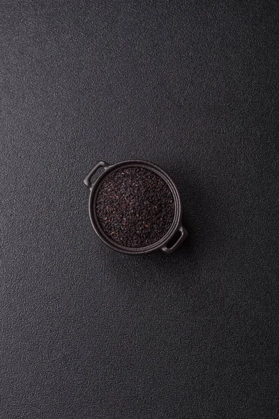 Bir kasede siyah susam tohumu, yağ ve sağlıklı yemek için bir malzeme. Tasarımınız için yiyecek arkaplanı olarak siyah susam