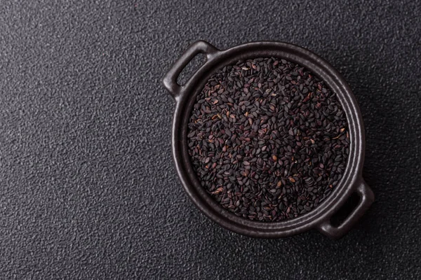 Bir kasede siyah susam tohumu, yağ ve sağlıklı yemek için bir malzeme. Tasarımınız için yiyecek arkaplanı olarak siyah susam