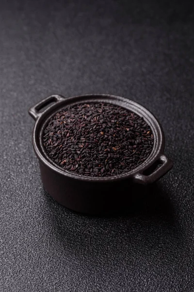 Bir kasede siyah susam tohumu, yağ ve sağlıklı yemek için bir malzeme. Tasarımınız için yiyecek arkaplanı olarak siyah susam