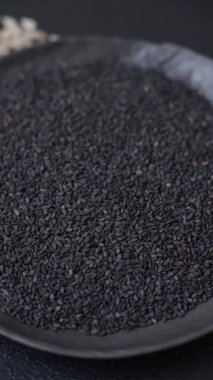 Bir kasede siyah susam tohumu, yağ ve sağlıklı yemek için bir malzeme. Tasarımınız için yiyecek arkaplanı olarak siyah susam