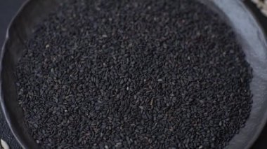 Bir kasede siyah susam tohumu, yağ ve sağlıklı yemek için bir malzeme. Tasarımınız için yiyecek arkaplanı olarak siyah susam