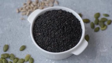 Bir kasede siyah susam tohumu, yağ ve sağlıklı yemek için bir malzeme. Tasarımınız için yiyecek arkaplanı olarak siyah susam