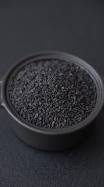 Bir kasede siyah susam tohumu, yağ ve sağlıklı yemek için bir malzeme. Tasarımınız için yiyecek arkaplanı olarak siyah susam