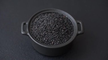 Bir kasede siyah susam tohumu, yağ ve sağlıklı yemek için bir malzeme. Tasarımınız için yiyecek arkaplanı olarak siyah susam