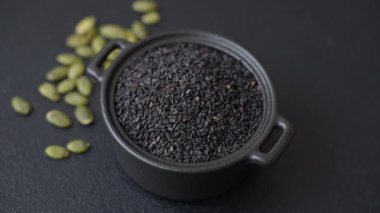 Bir kasede siyah susam tohumu, yağ ve sağlıklı yemek için bir malzeme. Tasarımınız için yiyecek arkaplanı olarak siyah susam