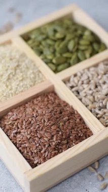 Bir kutu keten, balkabağı, ayçiçeği ve susam tohumu, sağlıklı beslenmek için malzemeler. Keten, susam, balkabağı ve ay çekirdeği tasarımınız için bir besin kaynağı.