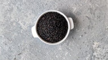 Bir kasede siyah susam tohumu, yağ ve sağlıklı yemek için bir malzeme. Tasarımınız için yiyecek arkaplanı olarak siyah susam