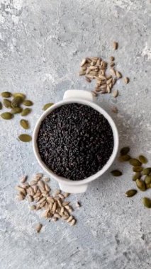 Bir kasede siyah susam tohumu, yağ ve sağlıklı yemek için bir malzeme. Tasarımınız için yiyecek arkaplanı olarak siyah susam