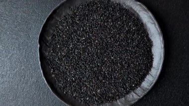 Bir kasede siyah susam tohumu, yağ ve sağlıklı yemek için bir malzeme. Tasarımınız için yiyecek arkaplanı olarak siyah susam