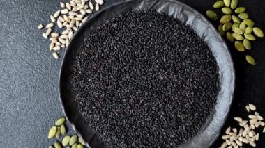 Bir kasede siyah susam tohumu, yağ ve sağlıklı yemek için bir malzeme. Tasarımınız için yiyecek arkaplanı olarak siyah susam