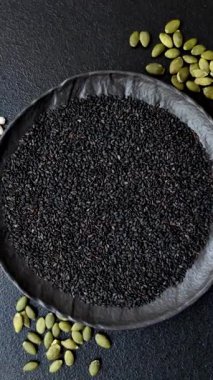 Bir kasede siyah susam tohumu, yağ ve sağlıklı yemek için bir malzeme. Tasarımınız için yiyecek arkaplanı olarak siyah susam