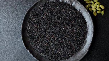 Bir kasede siyah susam tohumu, yağ ve sağlıklı yemek için bir malzeme. Tasarımınız için yiyecek arkaplanı olarak siyah susam